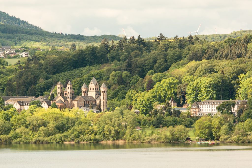 Die Abtei Maria Laach am Laacher See, umgeben von bewaldeten Hängen der Vulkaneifel