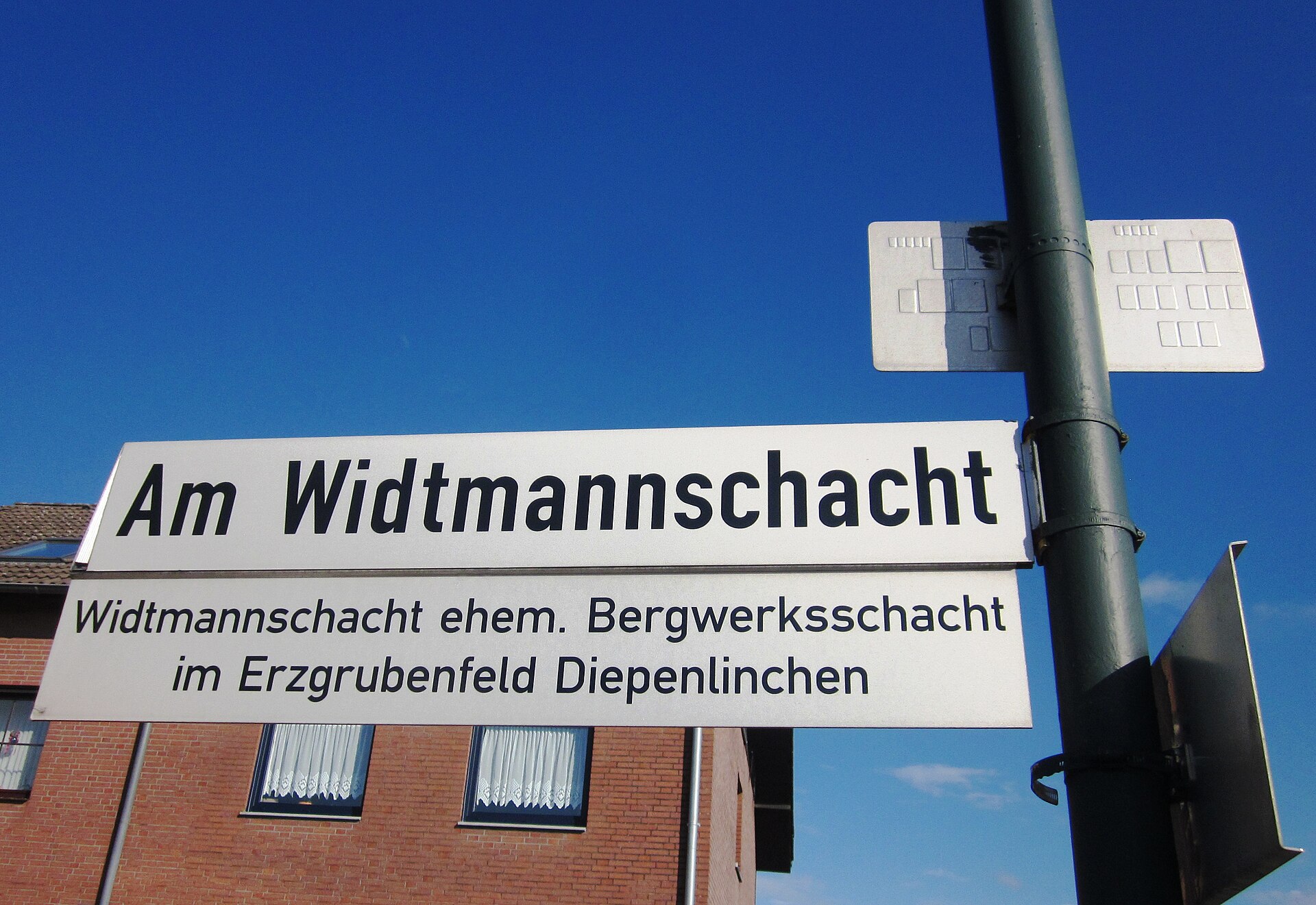 Straßenschild „Am Widtmannschacht“ mit dem Zusatz „ehem. Bergwerksschacht im Erzgrubenfeld Diepenlinchen“.