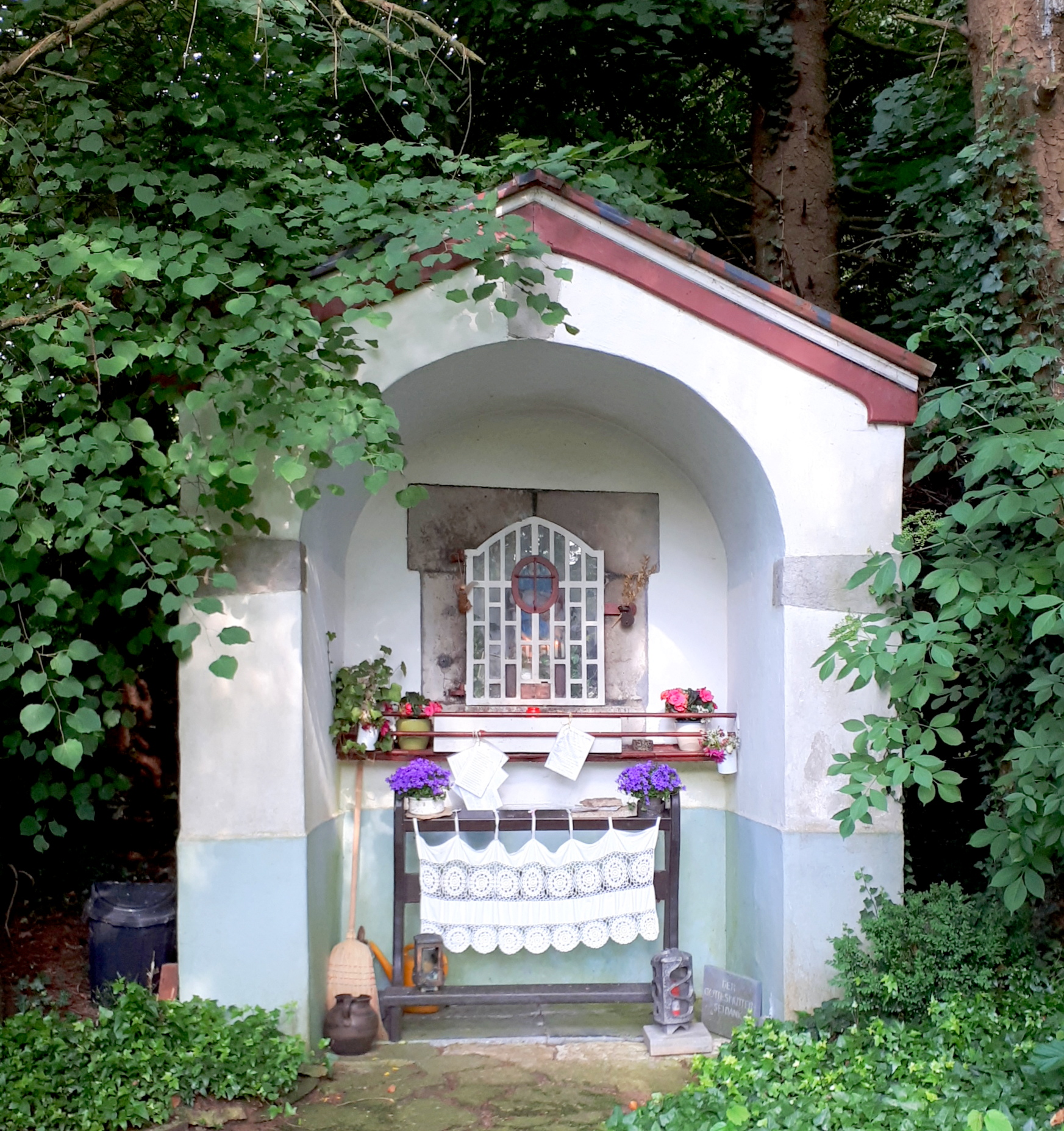 Die kleine weiß gestrichene Nikolauskapelle in Fleuth bei Stolberg-Mausbach, umgeben von Grün.