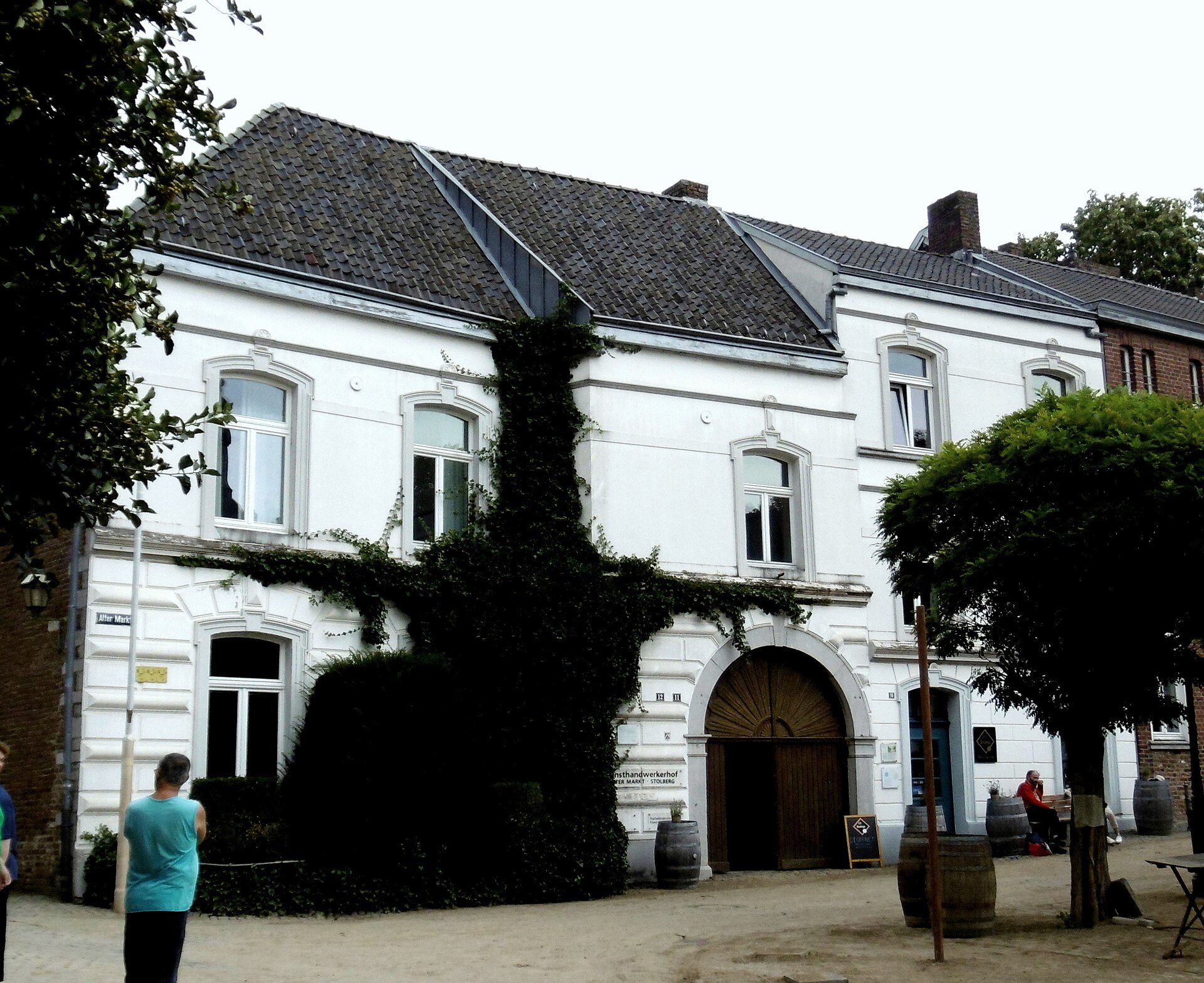 Der weiß verputzte Kupferhof Rose am Alter Markt in Stolberg mit Torbogen und efeubewachsener Fassade.