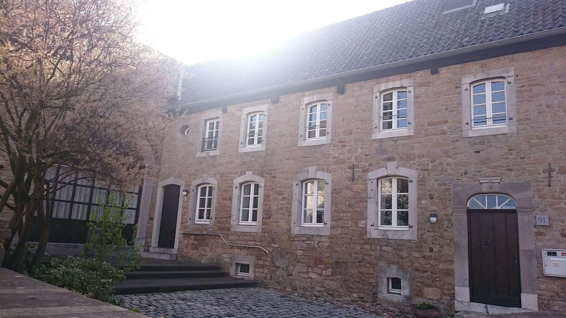 Ein denkmalgeschützter Winkelhof aus Bruchstein an der Vennstraße in Venwegen mit Torbogen.