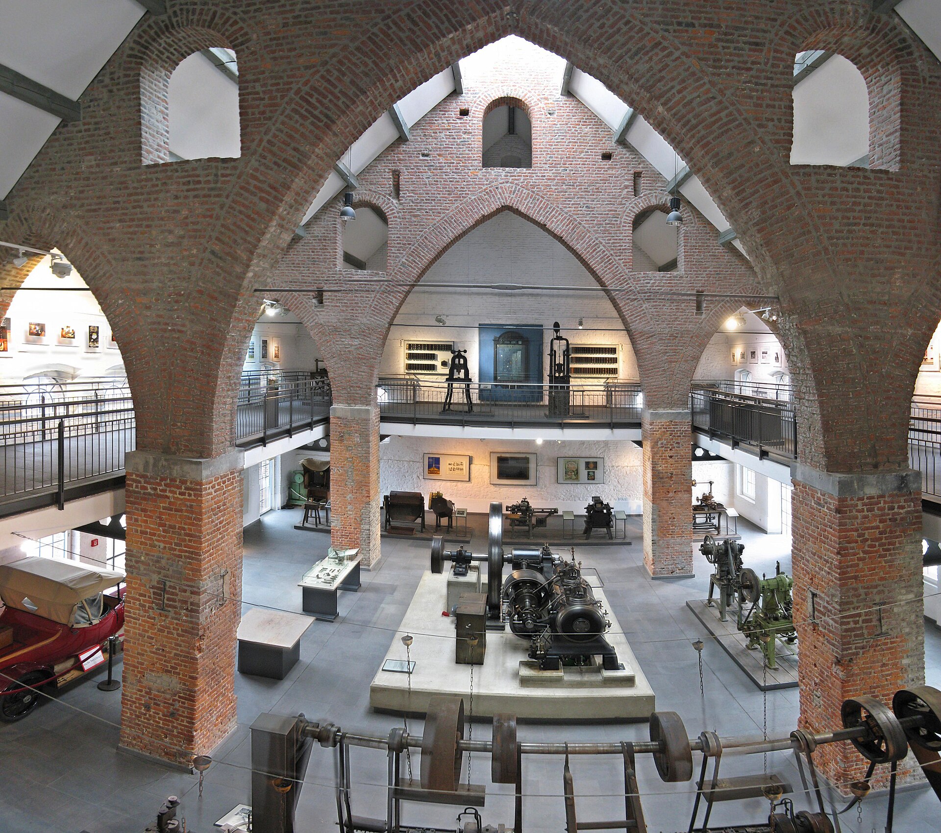 Blick in die Ausstellungshalle des Museums Zinkhütter Hof mit Backsteinbögen und Maschinen.